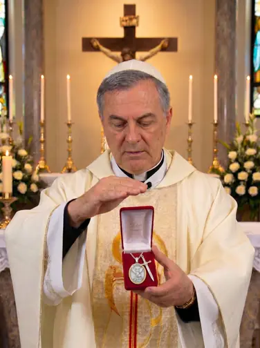 Padre abençoando o Colar de São Miguel diante do altar